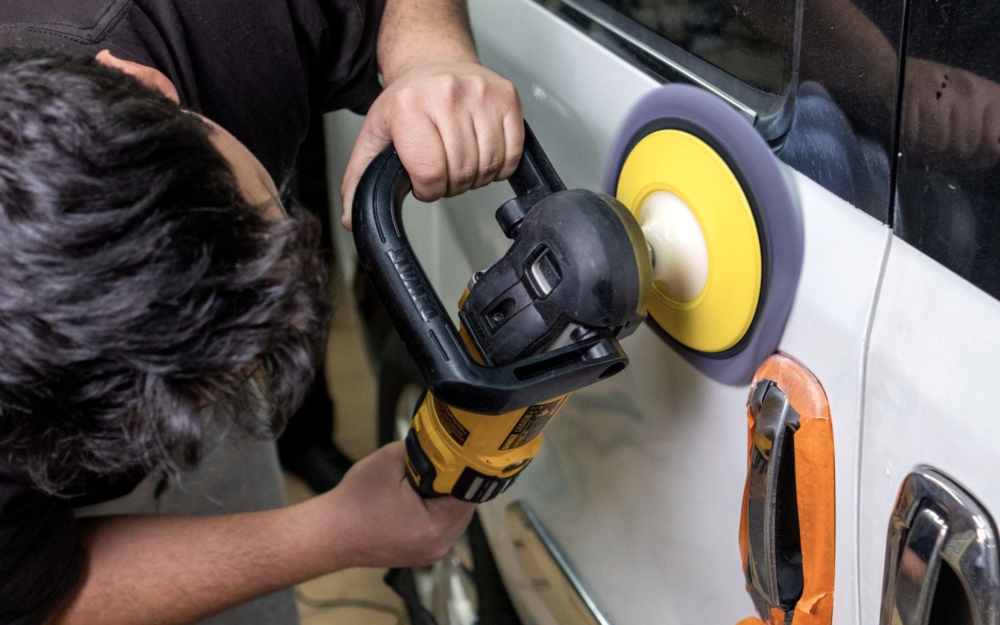 Machine polishing a car door during a professional detail