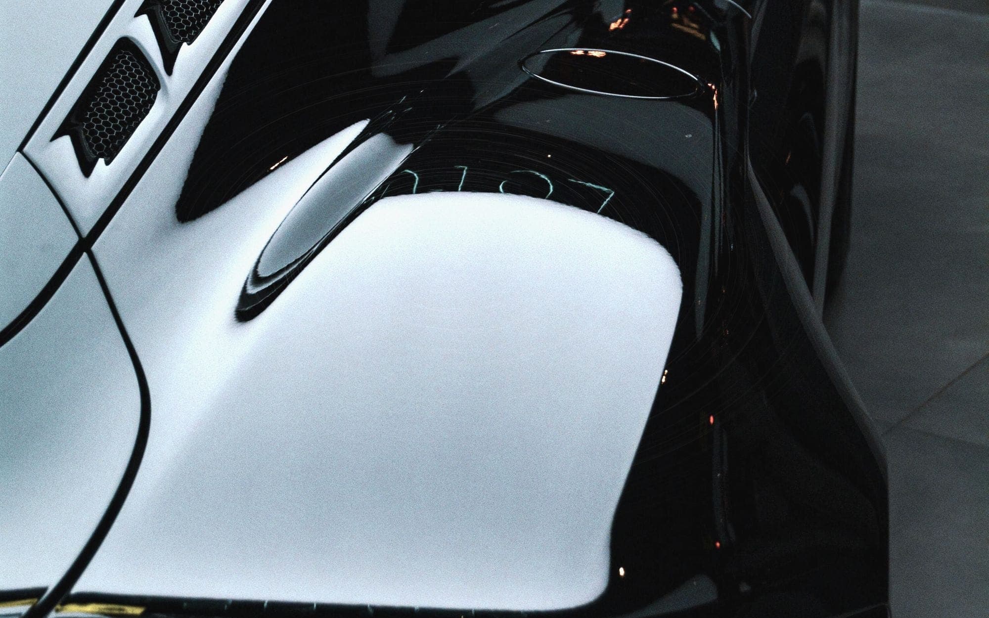 Glossy dark paint overlaid with a dense web of fine circular scratches